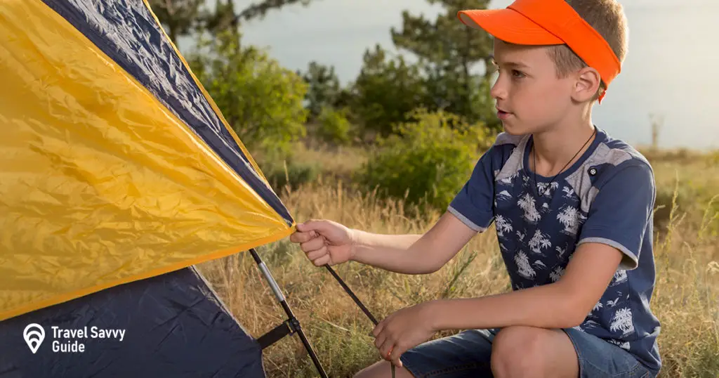 Boy in nature, in the forest sets up a tent and equips a bivouac