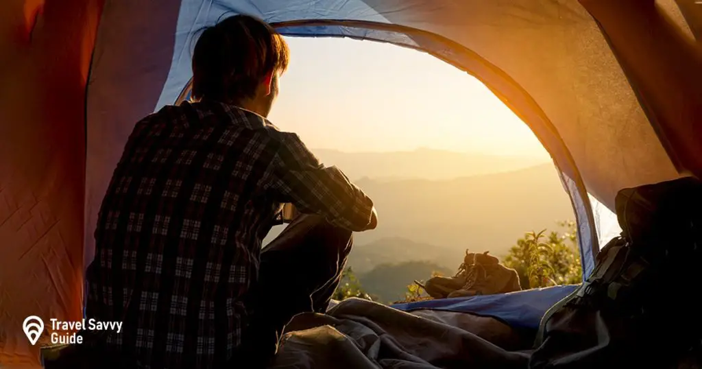 A young man sitting in the tent  holding coffee cup