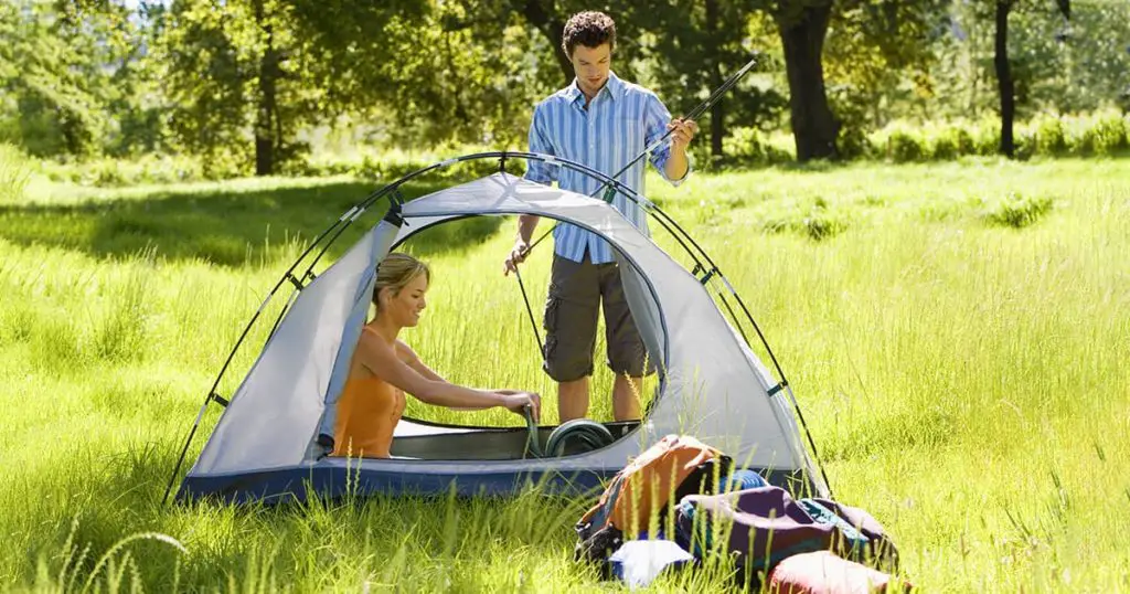 Young couple assembling pop up tent on camping trip