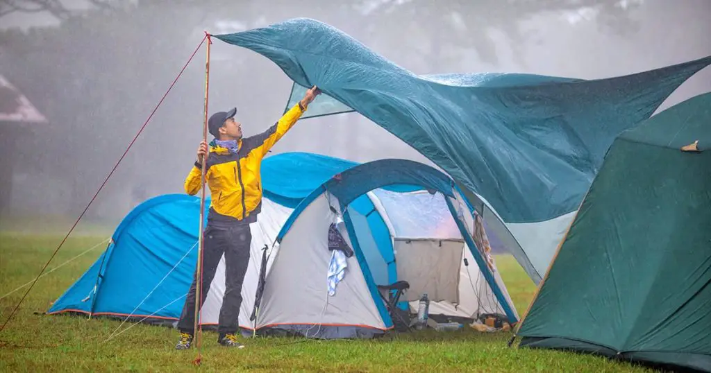 Traveler repairing tent during rain
