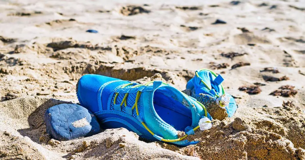 Close-up of shoes on sand at beach