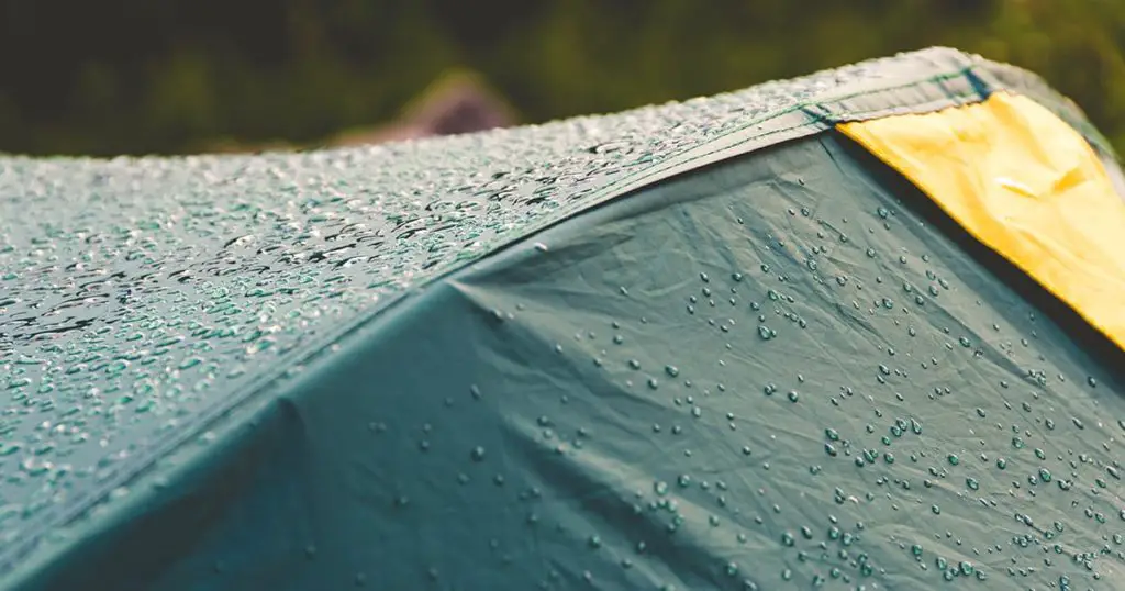 Dew drops on green tourist tent. Waterproof fabric rain, test of bad weather

