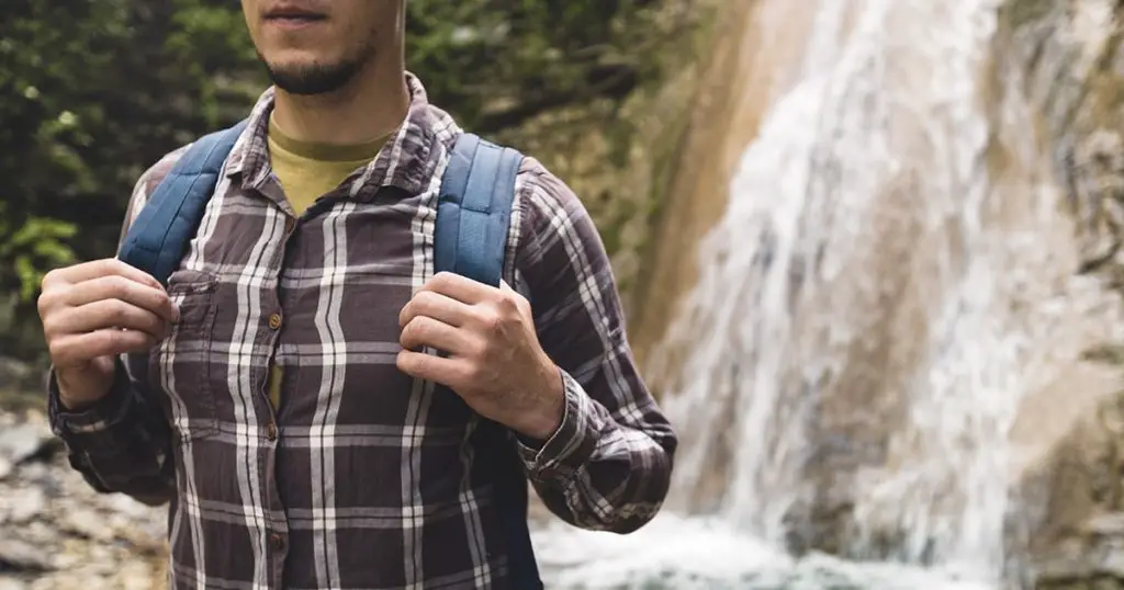 Traveler Explorer Hands Holds Backpack Strap On Waterfall Background Hiking Journey Travel Trek Concept