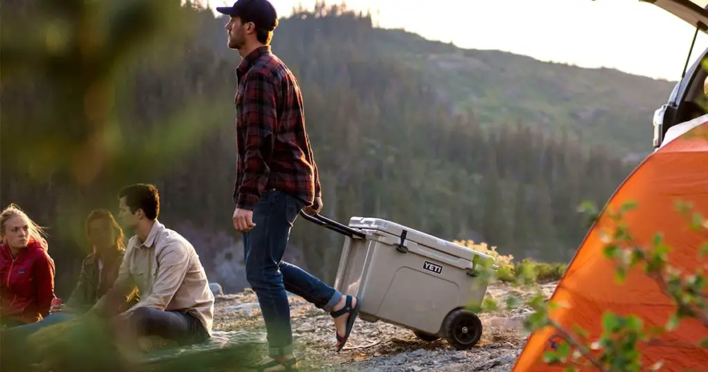 Man carrying a wheeled YETI hard cooler