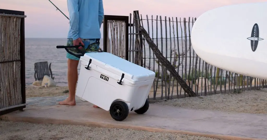 Man carrying a YETI wheeled cooler to be beach