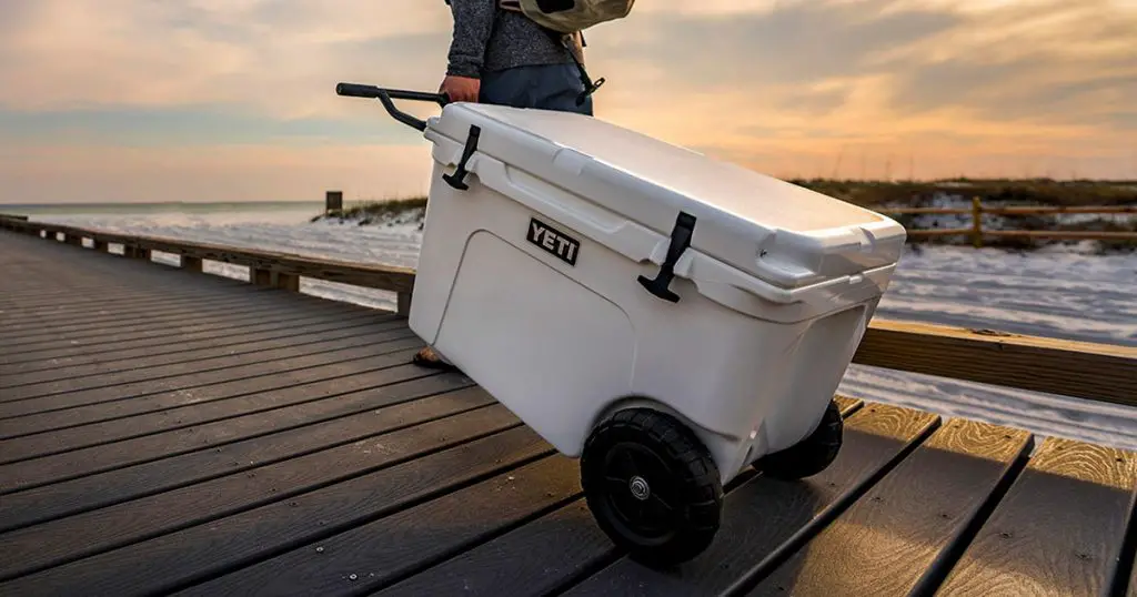 Man carring a YETI wheeled cooler on a bridge