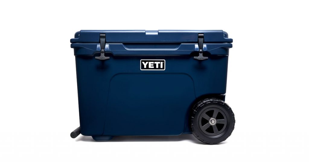 YETI navy color wheeled cooler a white background