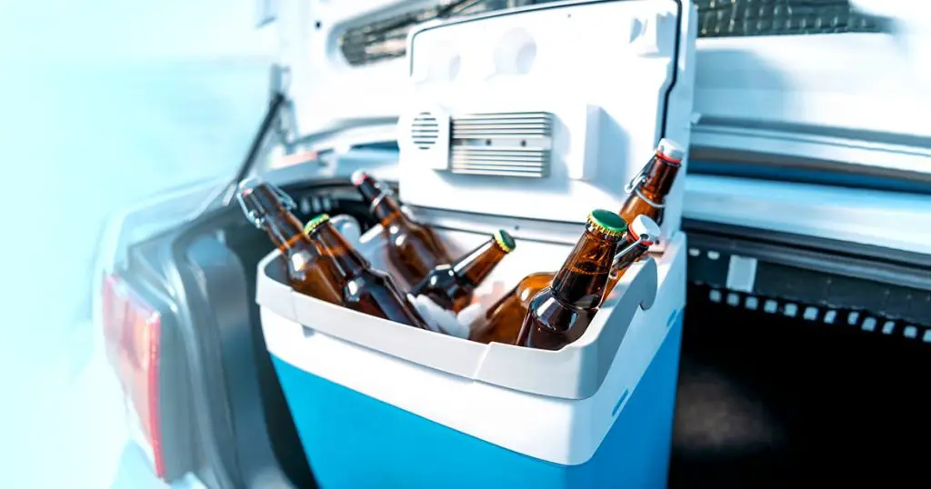 close up view of portable fridge with beer standing in car