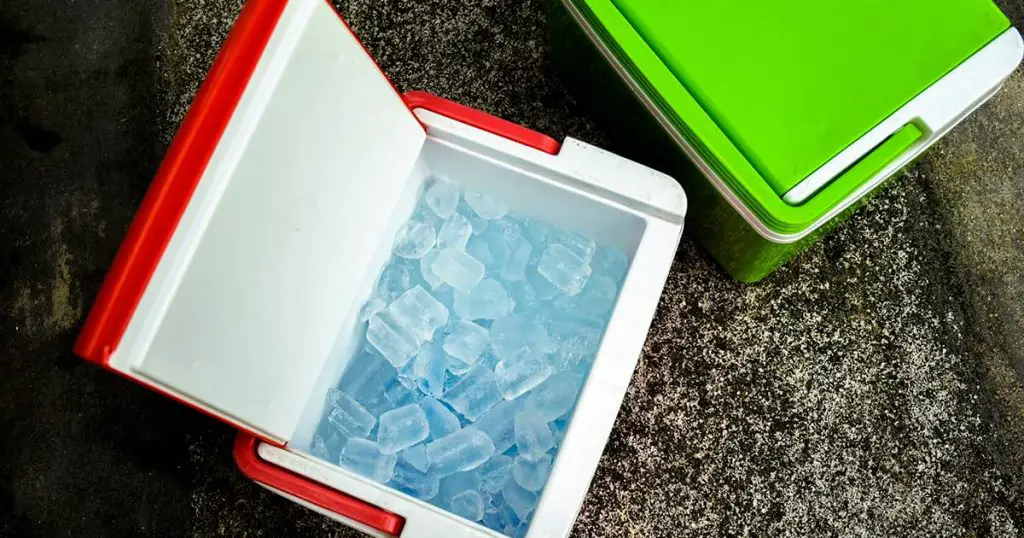 Top view of picnic cooler box with and ice cube on the ground for camping during summer vacation time