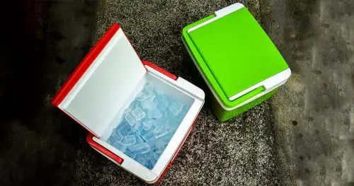 Top view of picnic cooler box with and ice cube on the ground for camping during summer vacation time