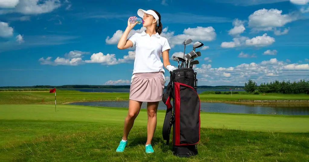 Young woman drinking water on a golf field