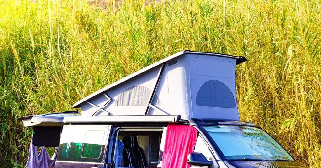 Camper van with roof top tent camping on mediterranean coast