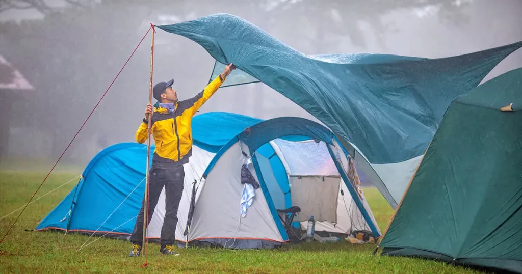 Traveler repairing tent during the rain