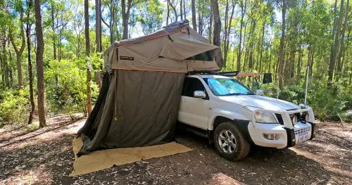 Recreation vehicle with roof top tent in a campsite