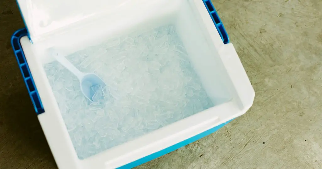 Top view of picnic cooler with ice cube on the ground