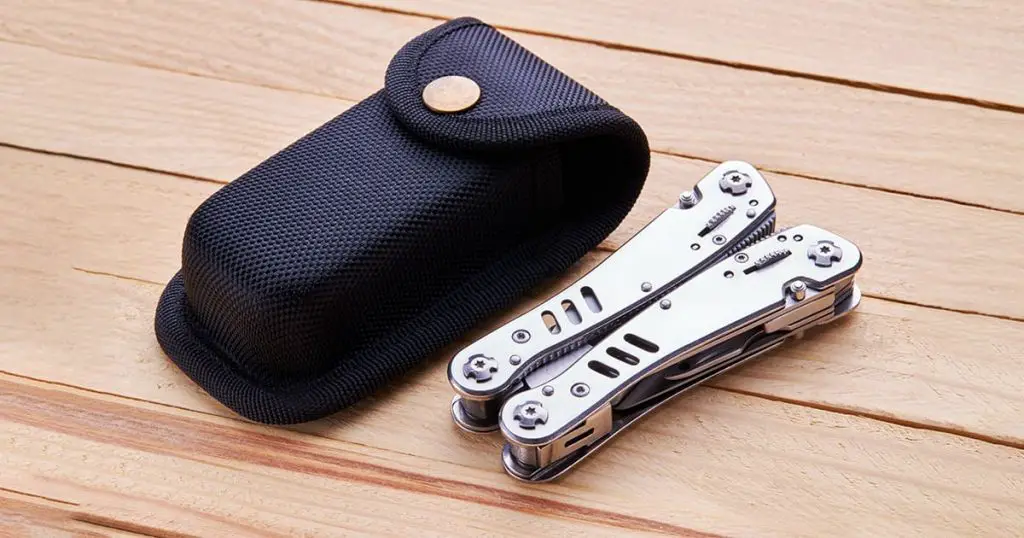 stainless steel multitool pocket knife. tourist survival tool over wooden desk background.