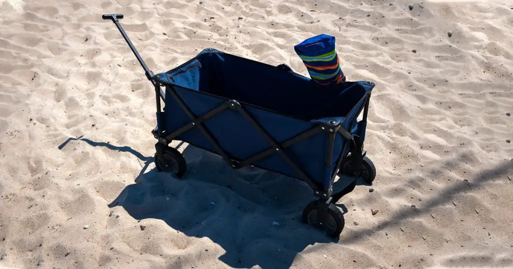 Blue empty beach cart with mat on the sand