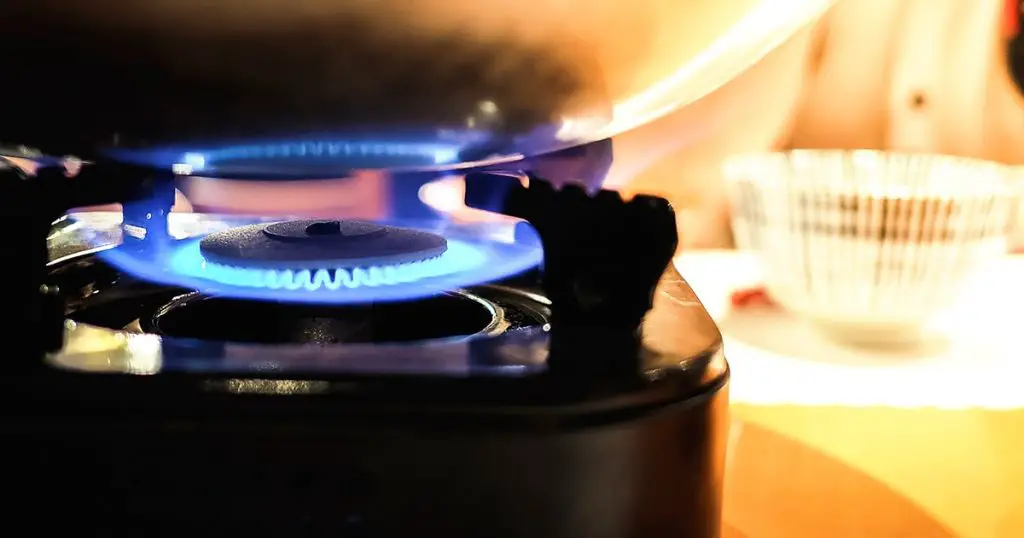 the blue fire from a portable gas stove heating the pot in Japanese Shabu-Shabu sukiyaki restaurant