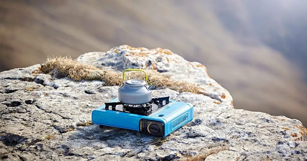 Portable tourist gas stove with a gray kettle on a background of nature in the mountains.