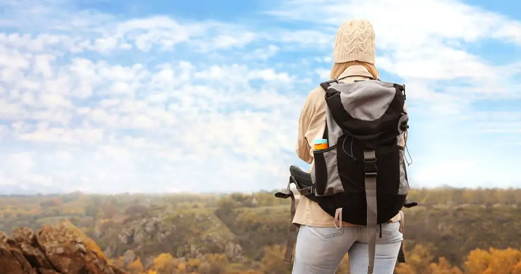 Traveler with backpack enjoying beautiful view on sunny day. Autumn vacation