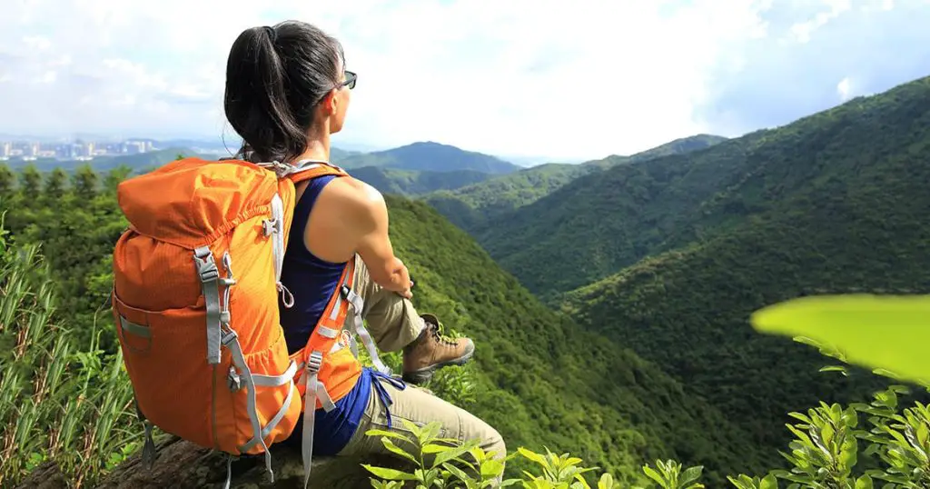 woman backpacker enjoy the view at mountain peak cliff