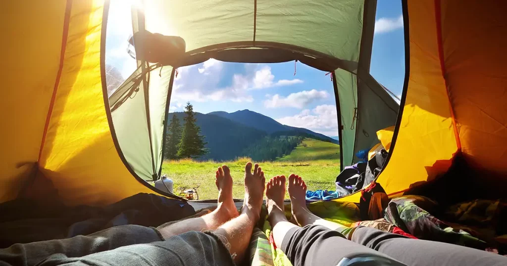 two-people-lying-tent-view-mountains