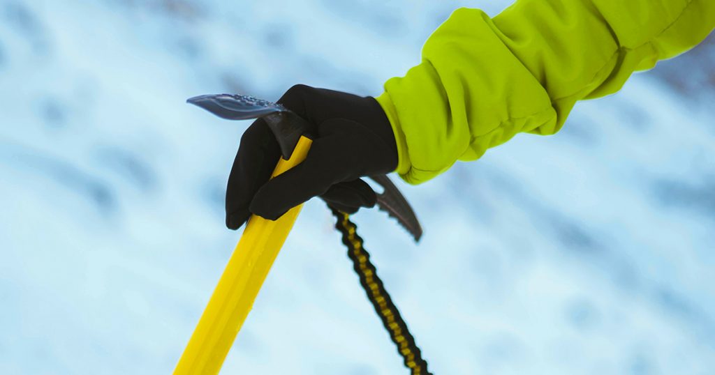 Hicking gloves and Yellow ice axe in the snow