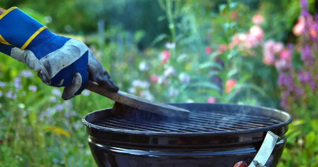 ale hand with gloves cleans round grill with stiff brush