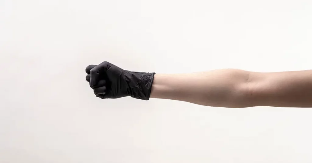Female hand in a black silicone glove. Hand clenched into a fist.