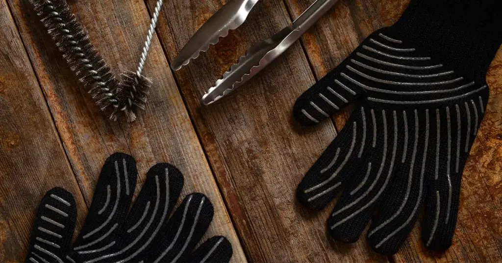 gloves and barbecue tools on wooden table