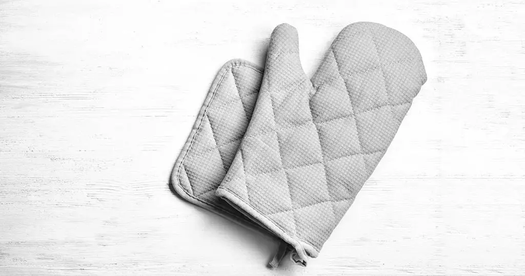 Oven glove and potholder on white wooden background, flat lay