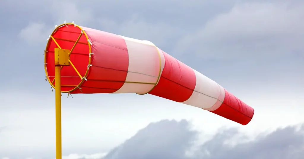 A windsock inflated by the wind against a cloudy sky.