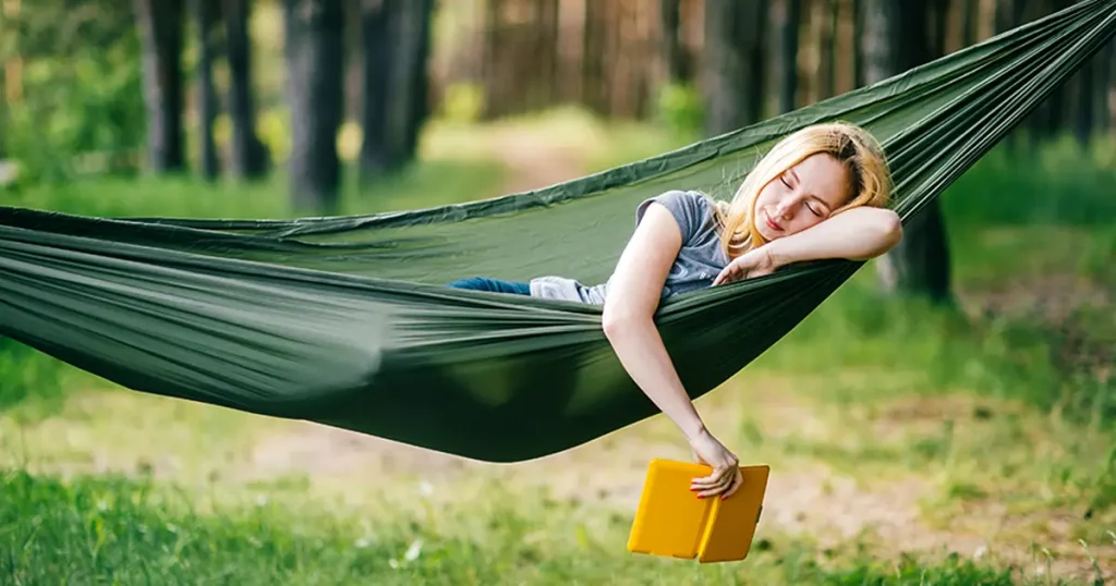 blonde girl sleeping in hammock in forest