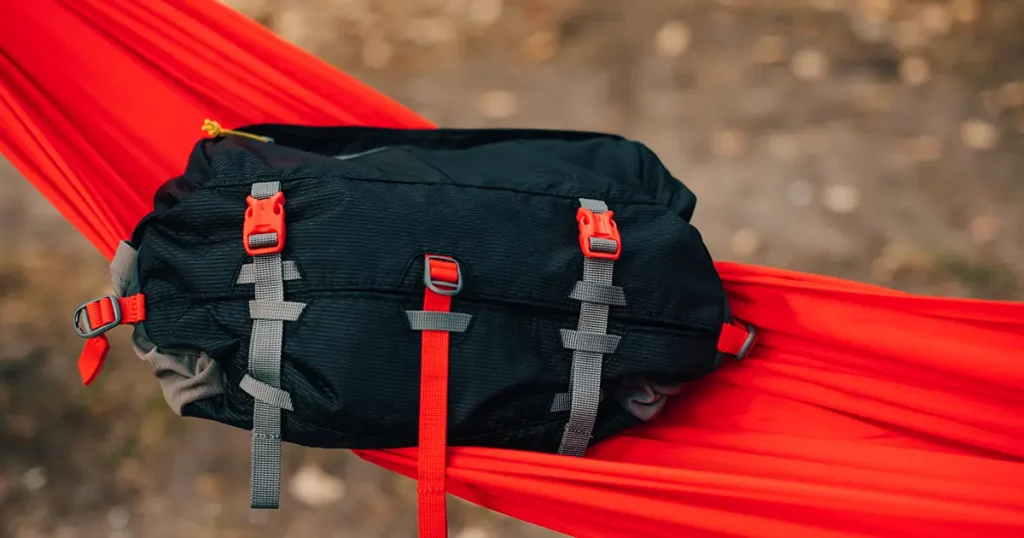 Travel waist bag lies on a red hammock in the woods