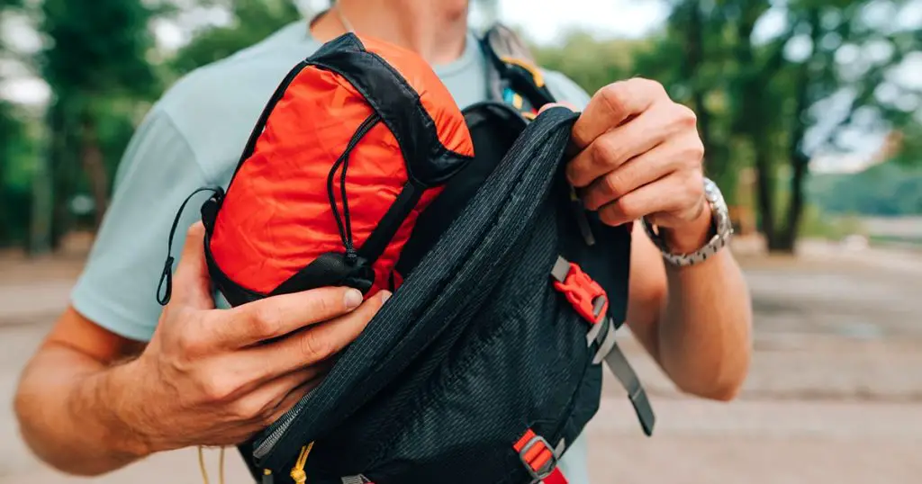 tourist puts a red bag with travel gear in a waist bag which he carries on his shoulder