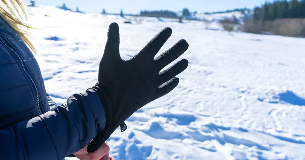 Woman putting winter sport glove in hand, getting ready for extreme cold weather