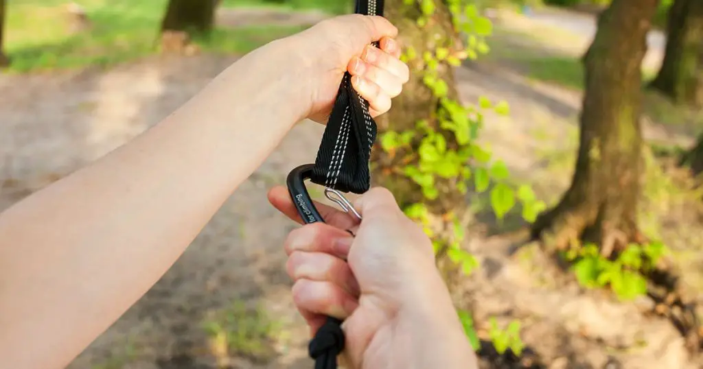 Closeup of woman hands attach the hammock straps on the tree