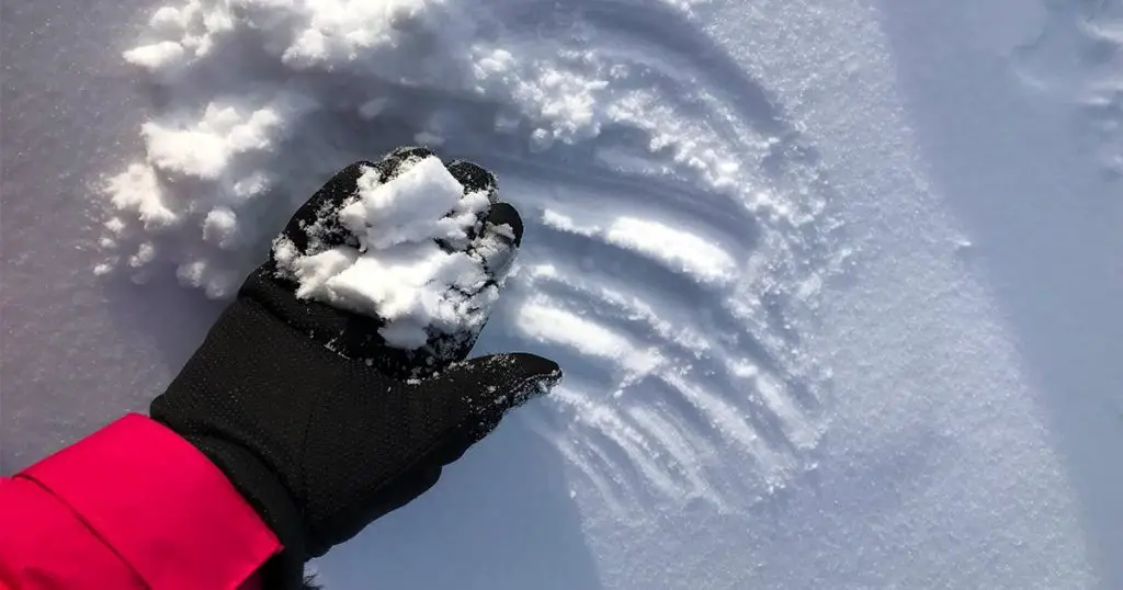 Hand holding snow wear black gloves pink jacket snow covered landscape mountain winter time chilly season adventurer