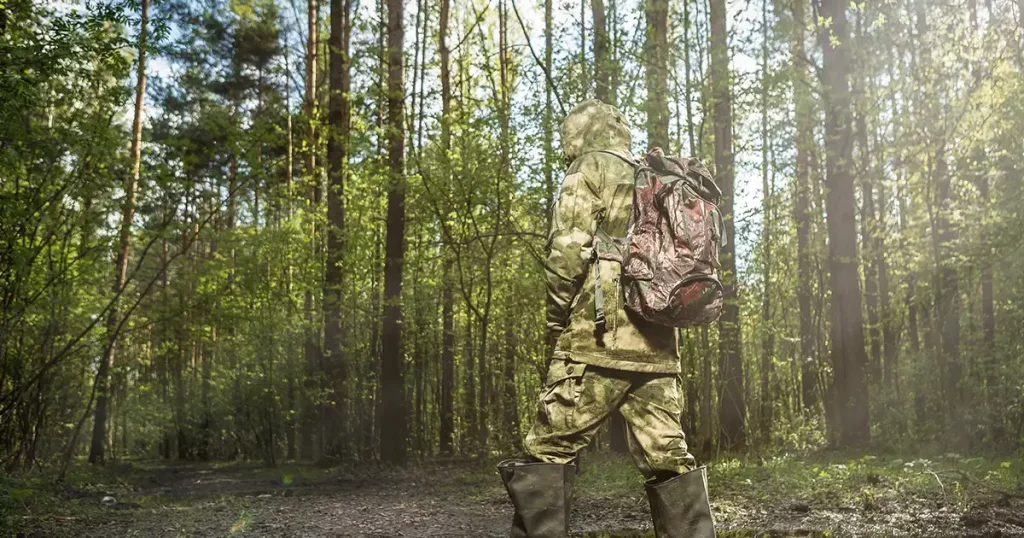 Man in the woods dressed in camouflage with backpack