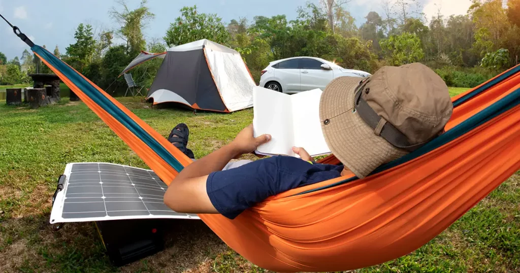 Relaxed man reading a book and lying in a comfortable hammock