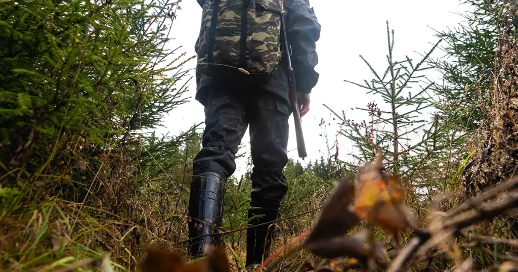 Hunter with a gun and a backpack in the forest