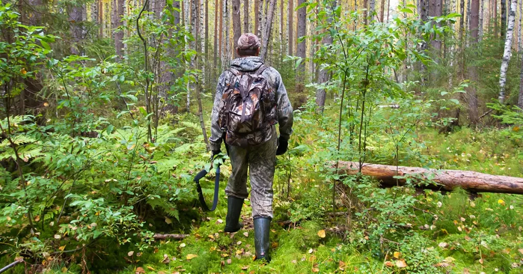 hunter in hunting camouflage with shotgun walking in the autumn forest