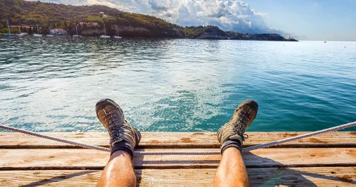 Tourist resting sitting shoes boots feet legs beach deck view