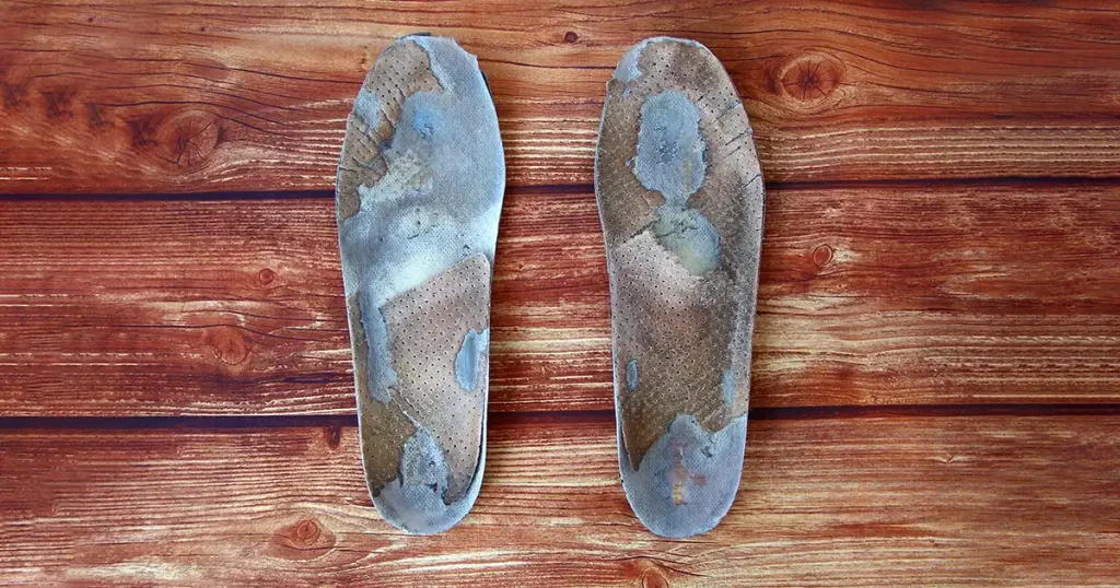 Old dirty orthopedic insoles on the wooden background