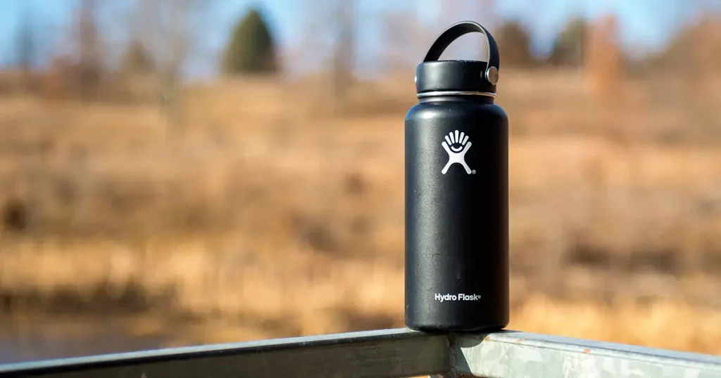 A Hydro Flask metal water bottle on a thin metal railing
