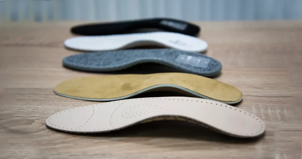 Orthopedic insoles are lined up on a wooden surface