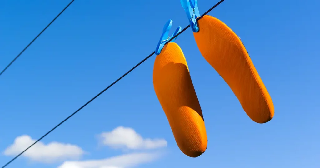 Orange footwear insoles drying on clothes or laundry line