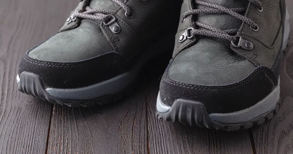 Dark boots with shoelace on wooden background