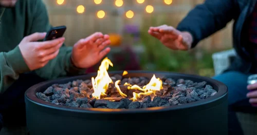 Two guys sitting around a backyard fire pit in autumn