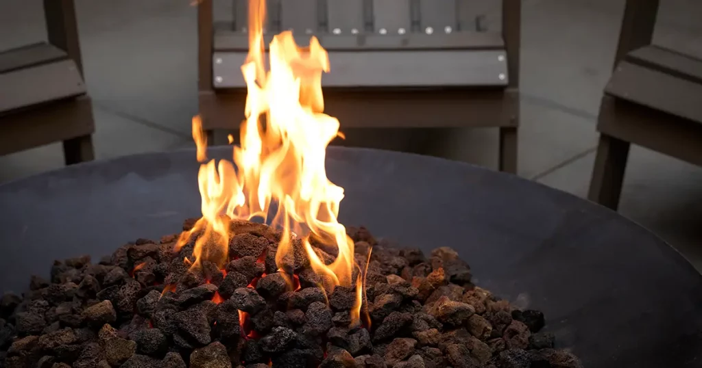 Close up on glowing lava rock coals in a black iron fire pit
